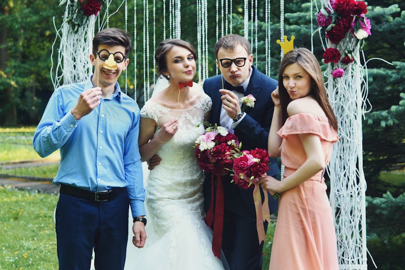 elegant stylish happy guests and bride and groom having funny photos on the background of arch, phot...