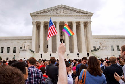 A man holds a U.S. and a rainbow flag outside the Supreme Court in Washington after the court legali...