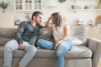 Positive couple having conversation while resting on sofa at home
