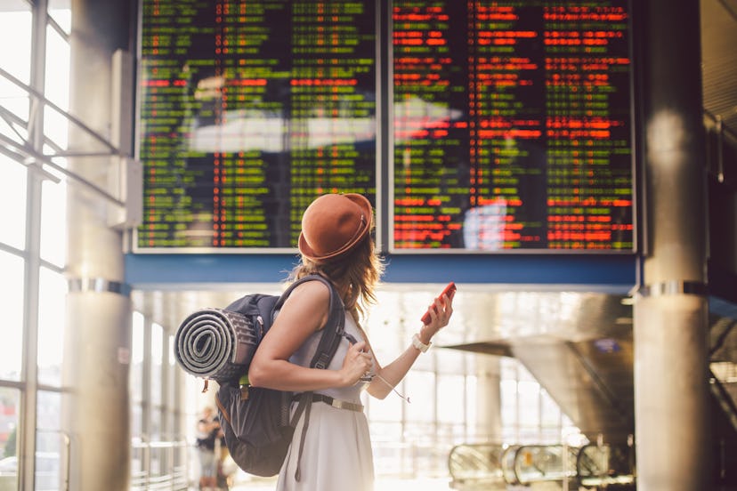 Theme travel and tranosport. Beautiful young caucasian woman in dress and backpack standing inside t...