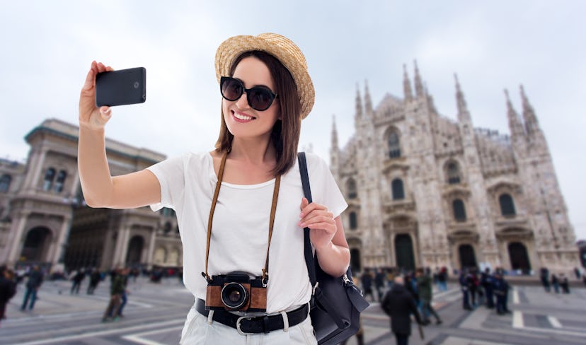 portrait of young beautiful woman tourist taking selfie photo with smartphone in Milan, Italy