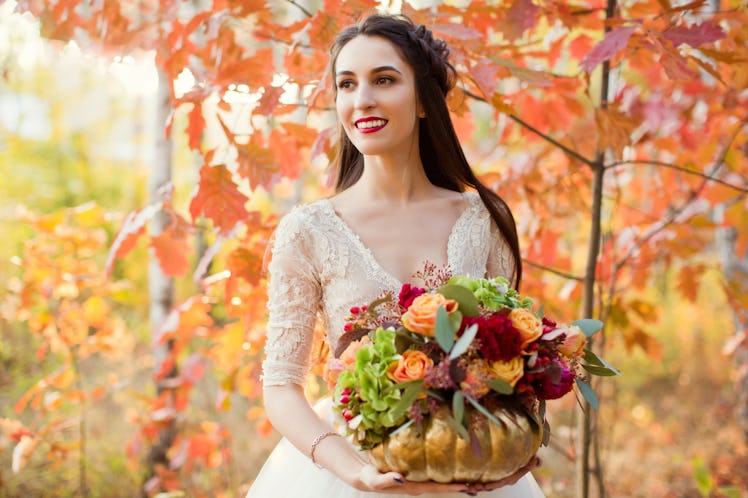beautiful bride with flowers in the golden pumpkin