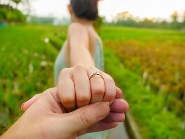 close up couple hands man holding happy fiance hand with diamond engagement ring on her finger after...