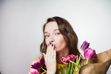 happy young girl holding a bouquet of flowers in her hands, sending an air kiss, celebrating the wor...