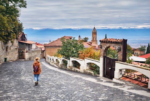 Tourist woman in hat with backpack at the street of Signagi town in Georgia
