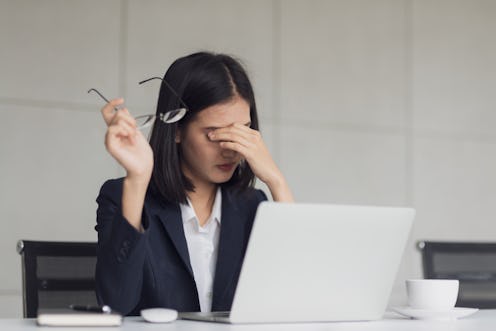 Young Asian business woman felling tired and have an eye pain after work with computer monitor for a...