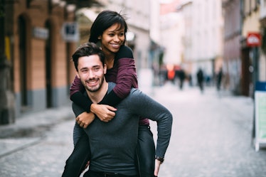 Young man giving girlfriend piggyback ride