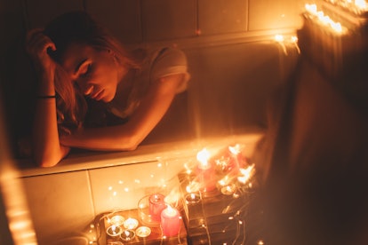 Red candles burning, Christmas lights and garland in bathroom on back bath. Romantic , Valentine's d...