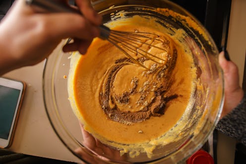 pumpkin pie recipe concept - woman whisking in cinnamon and spices for batter shot from pov view