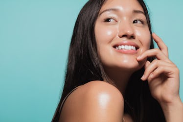 Close up of cute asian girl with glowing skin against blue background. Beautiful face of girl with f...