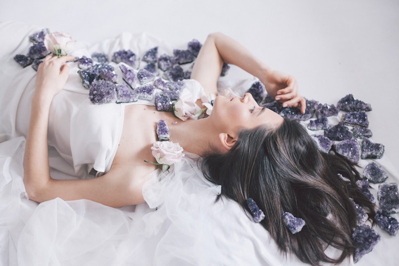 A woman lies among flowers. these are the best crystals for stress relief.