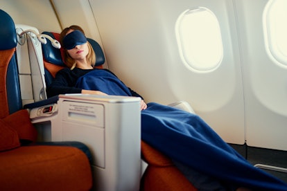 Traveling at first class. Flight with comfort. Pretty young  woman sleeping in airplane.