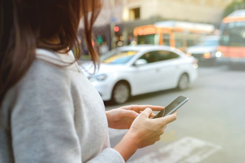 Close-up on woman hands holding smartphone in the center of the city.