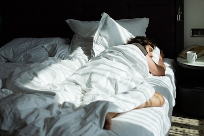 Blond young man is sleeping in a white bed
