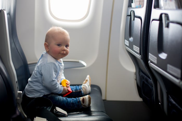 Cute baby boy, playing with toys on board of aircraft, traveling on vacation with parents and siblin...