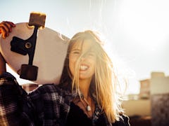 nice caucasiamo blonde model free woman with a skateboard in the sun backlight at sunset. freedom an...