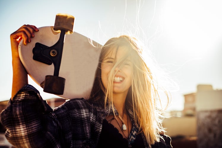 nice caucasiamo blonde model free woman with a skateboard in the sun backlight at sunset. freedom an...