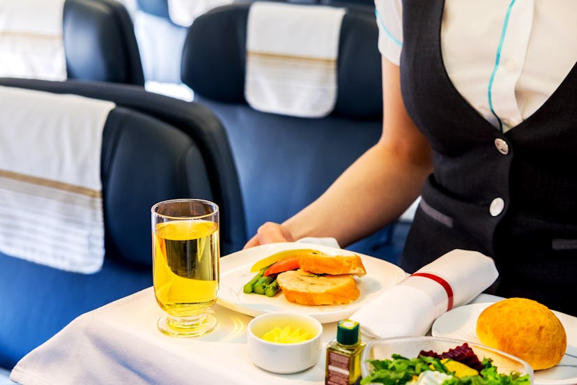 Mid section view of an air hostess carrying a tray of food