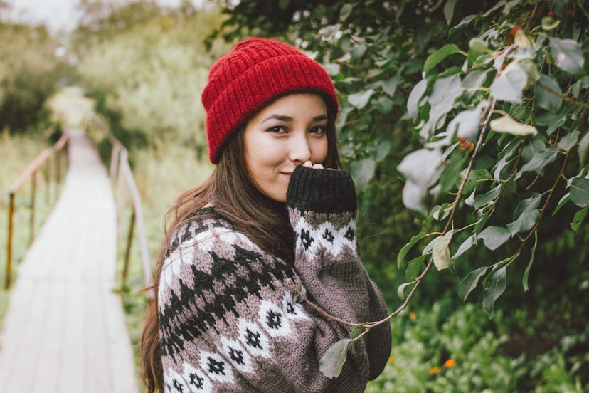 Beautiful carefree long hair asian girl in red hat and knitted nordic sweater in autumn nature park,...