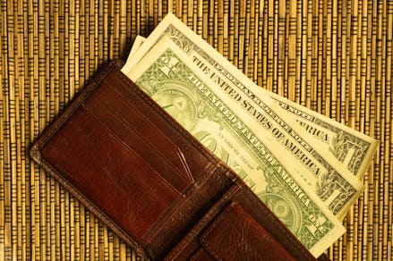Dollars in a wallet on a wooden bamboo background. money on the table. finance background