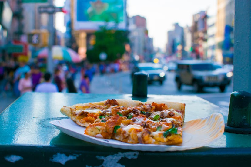 A slice of pizza in the middle of busy China Town, New York City