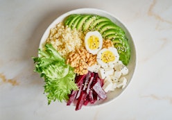 Buddha bowl, balanced food, vegetarian menu. Grey marble table, top view. Eggs, avocado, salad lettu...