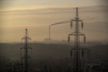 Smoke rises from the chimney of the incineration plant with high voltage lines in the foreground dur...