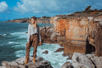 Beautiful woman posing on rocky cliff at Cascais , Portugal