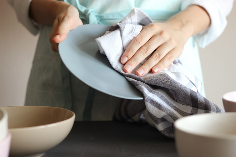 Housewife wipes the dishes with a towel.
