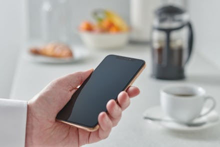 Close Up Detail Of A Man Holding A Smartphone Over A Kitchen Counter