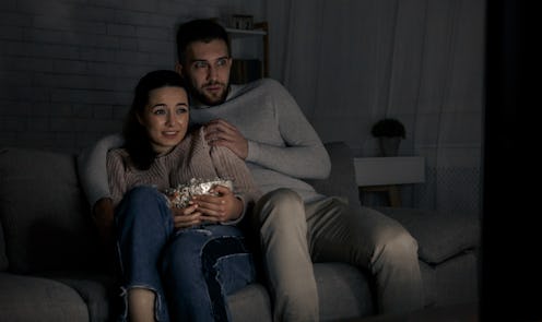 Scared couple watching horror film late at night at home
