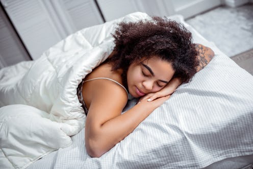 Dark-skinned woman resting. Curly short-haired lady putting head down on connected hands during deep...