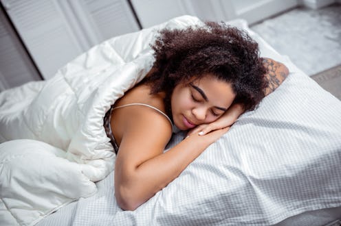 Dark-skinned woman resting. Curly short-haired lady putting head down on connected hands during deep...