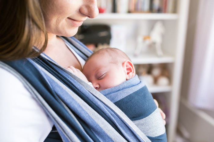 Unrecognizable young mother with her son in sling