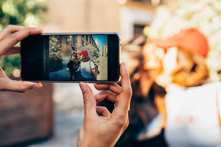 Girl's hands taking photo of a couple of women kissing in a street of Madrid. Same sex relationship ...