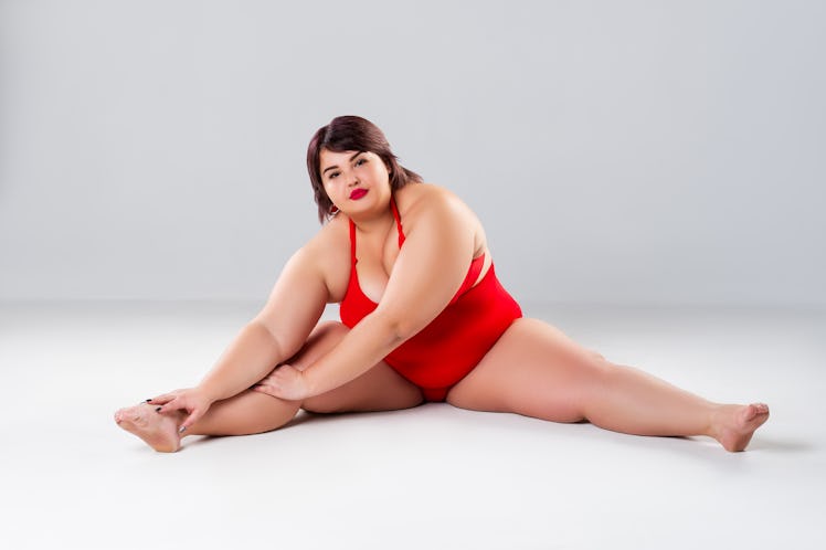 Plus size model in red lingerie, fat woman in underwear on gray studio background, body positive con...