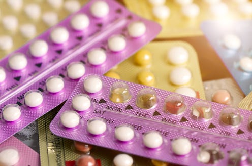 Oral contraceptive pill on pharmacy counter with colorful pills strips background.
