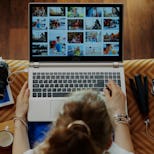 Upper view of stylish woman sitting on couch in the modern living room looks at image library while ...