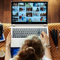 Upper view of stylish woman sitting on couch in the modern living room looks at image library while ...