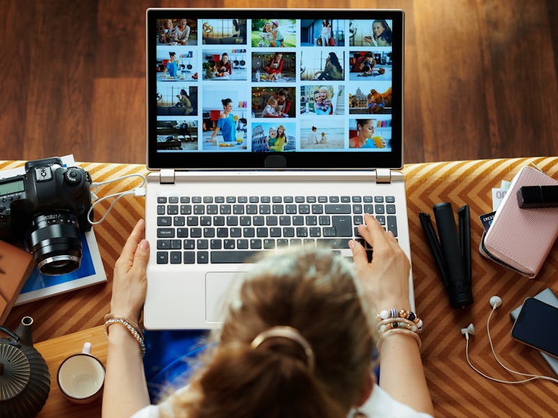 Upper view of stylish woman sitting on couch in the modern living room looks at image library while ...