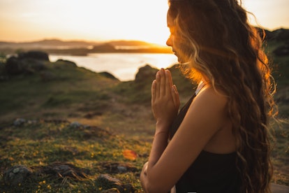 Woman praying alone at sunrise. Nature background. Spiritual and emotional concept. Sensitivity to n...