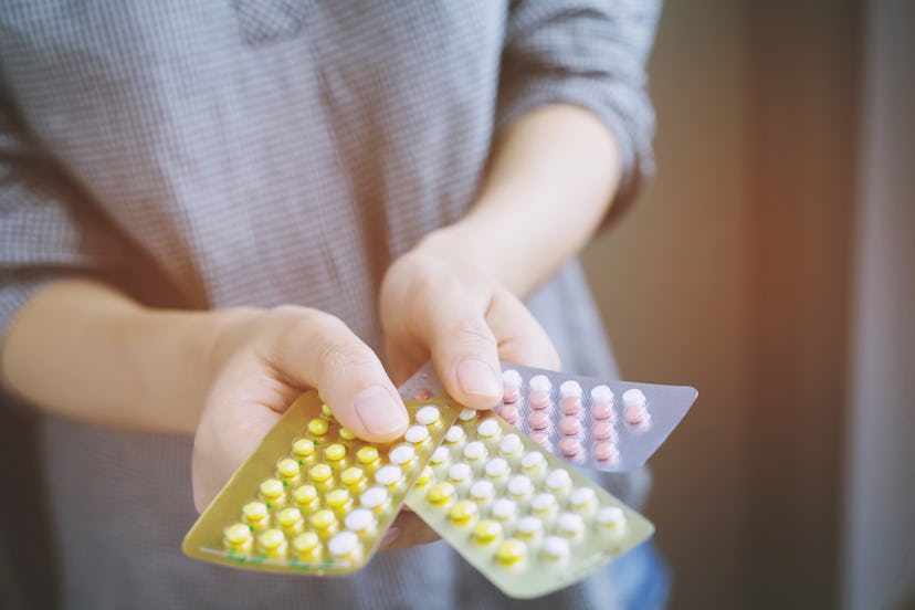 Close up  young women hand contraceptive pill on with colorful pills strips. Contraception reduces c...