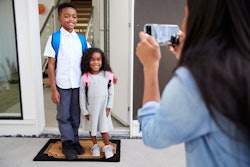 Mother Taking Photo Of Children With Cell Phone On First Day Back At School