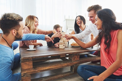 Group of creative friends sitting at wooden table. People having fun while playing board game.