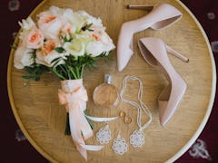 Botanic bridal chic. Bouquet with silk ribbons, female classic shoes, perfume bottle, necklace, earr...