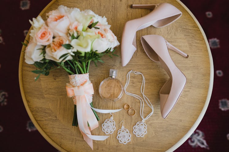 Botanic bridal chic. Bouquet with silk ribbons, female classic shoes, perfume bottle, necklace, earr...