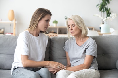 Loving adult daughter talking to sad old mother holding hand comforting upset older woman having pro...