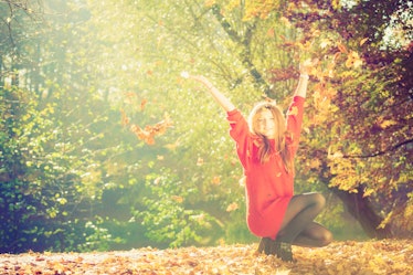 Autumn time. Fun and carefree. Cheerful lovely young woman playing with leaves. Girl relax in autumn...