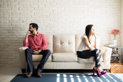 Husband and wife sitting on the couch and not talking after an argument at home