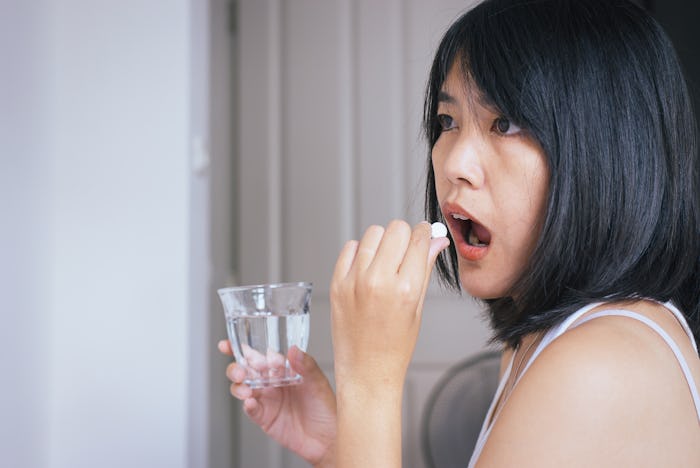 Woman sick with pill putting in her mouth,female taking medicines and a glass of water,Concept for h...